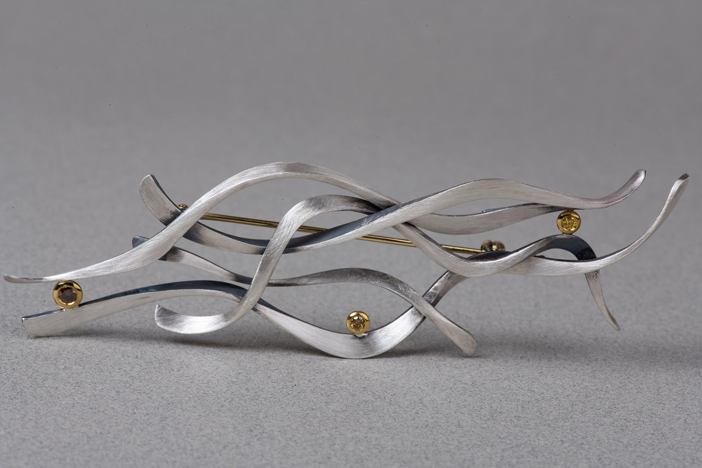 front of abstract brooch in sterling, gold, and diamonds