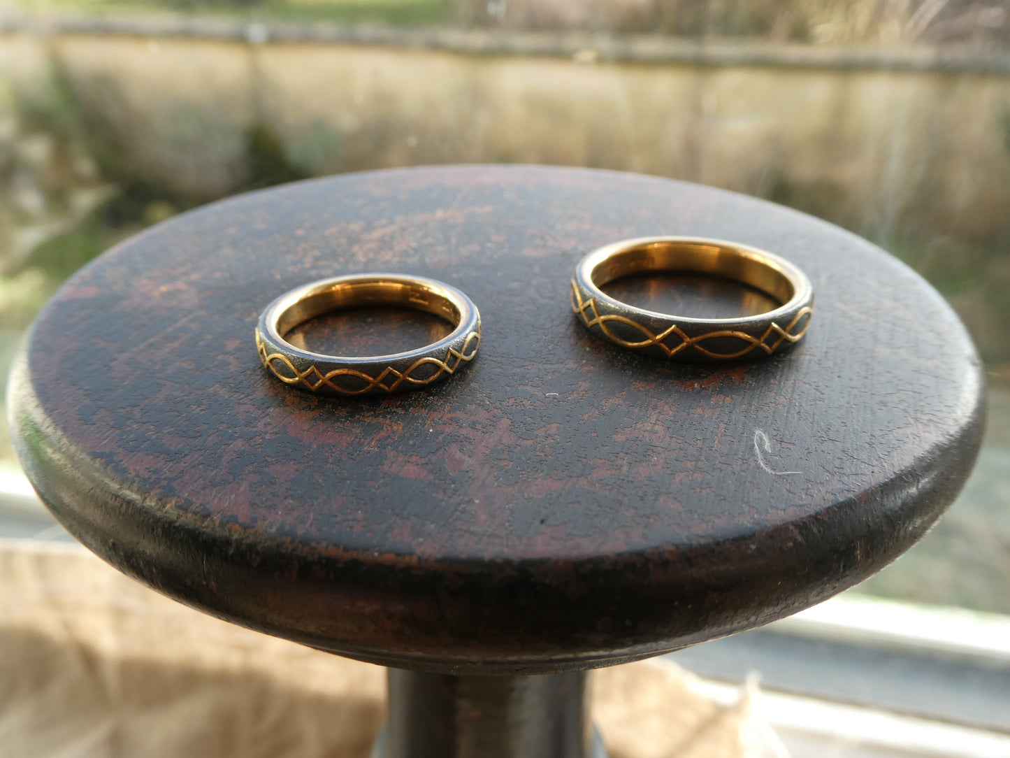 gold inlaid wedding bands with design set against blackened silver