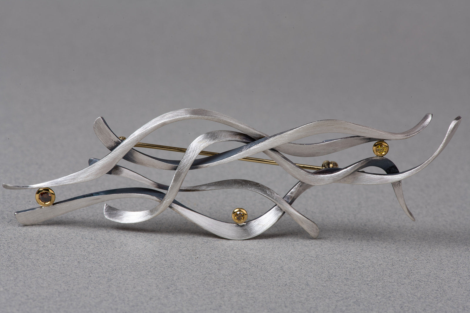 front of abstract brooch in sterling, gold, and diamonds